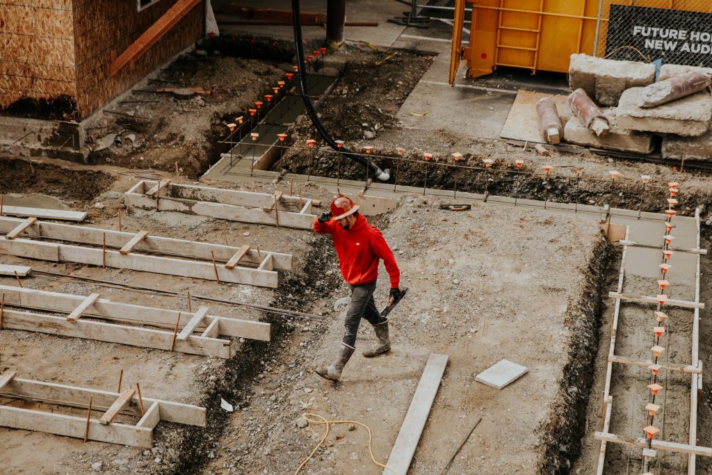 Plac budowy, mężczyzna w czerwonym kasku i bluzie