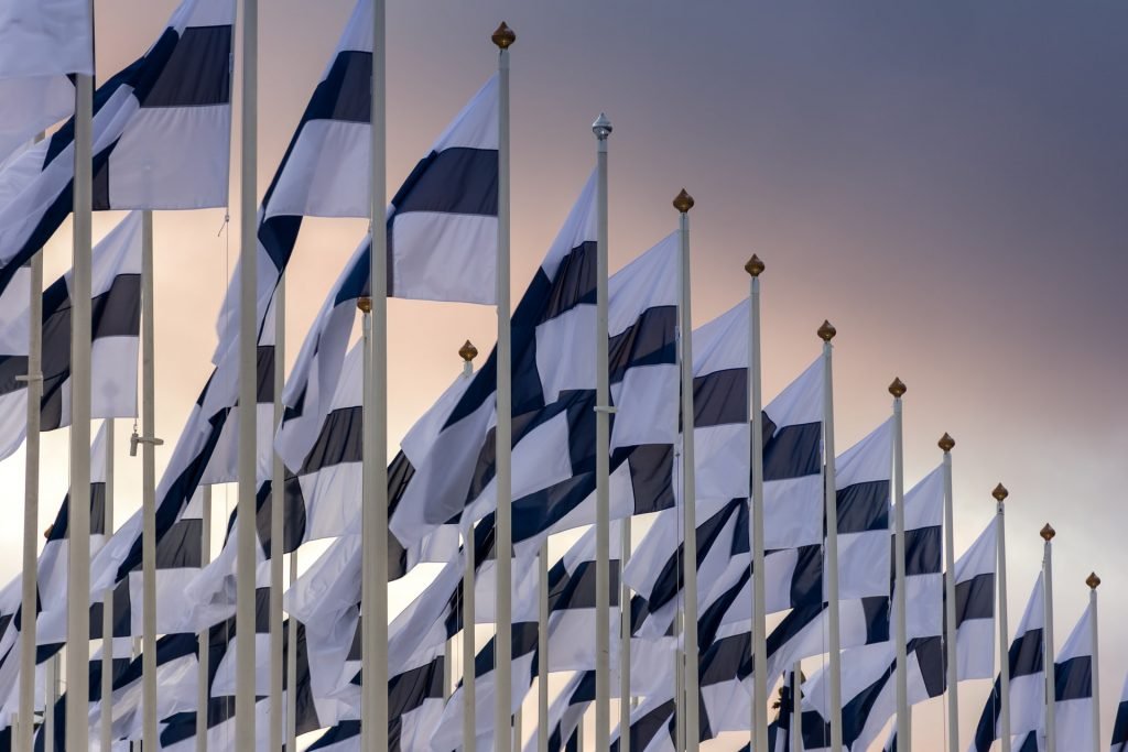 Finlandia w NATO Szereg flag Finlandii na zachodzącym niebie