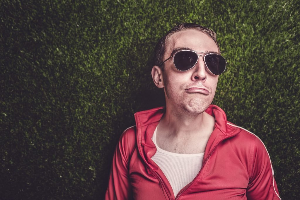 Mężczyzna w dresowej bluzie w okularach robi dziwną minę