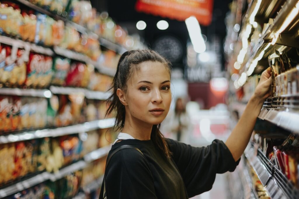 SSB chce śledzić twoje wydatki. Norweski Urząd Ochrony Danych nie pozwala Młoda kobieta z ciemnymi włosami spiętymi w kucyk stoi przy półce sklepowej w supermarkecie.