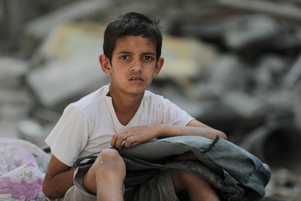 Palestyński chłopiec siedzący na gruzach 