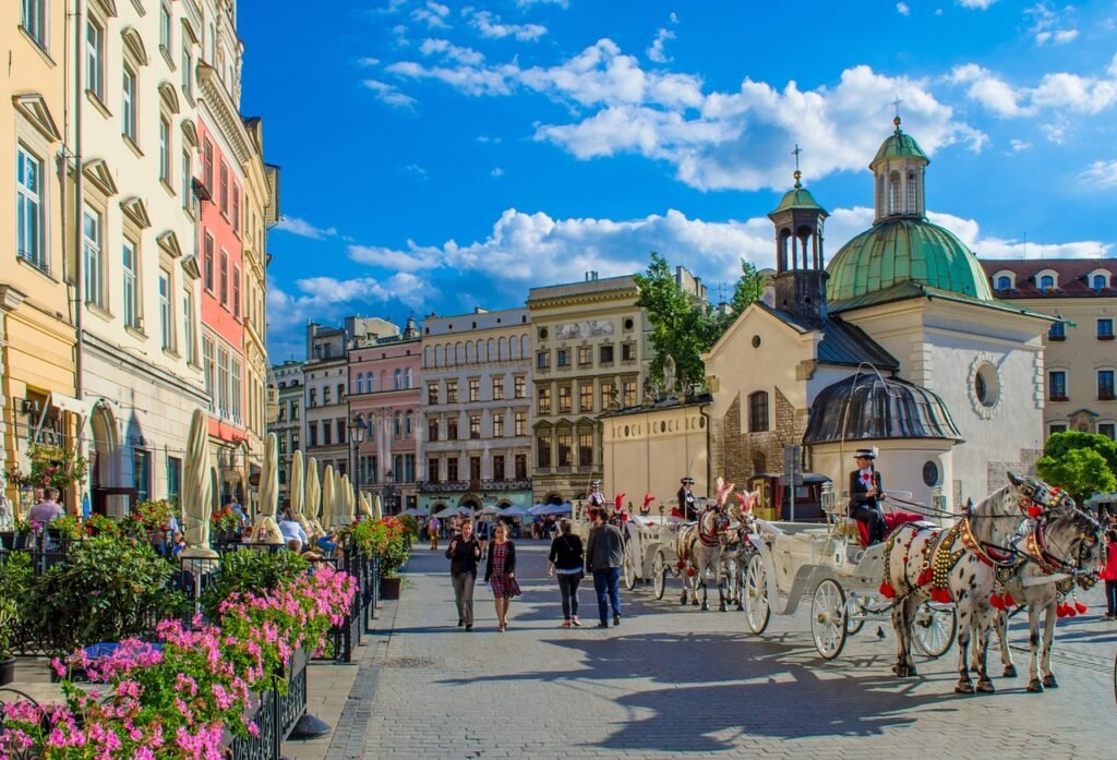 Kraków rynek latem. Kościół św. Wojciecha, bryczka, turyści