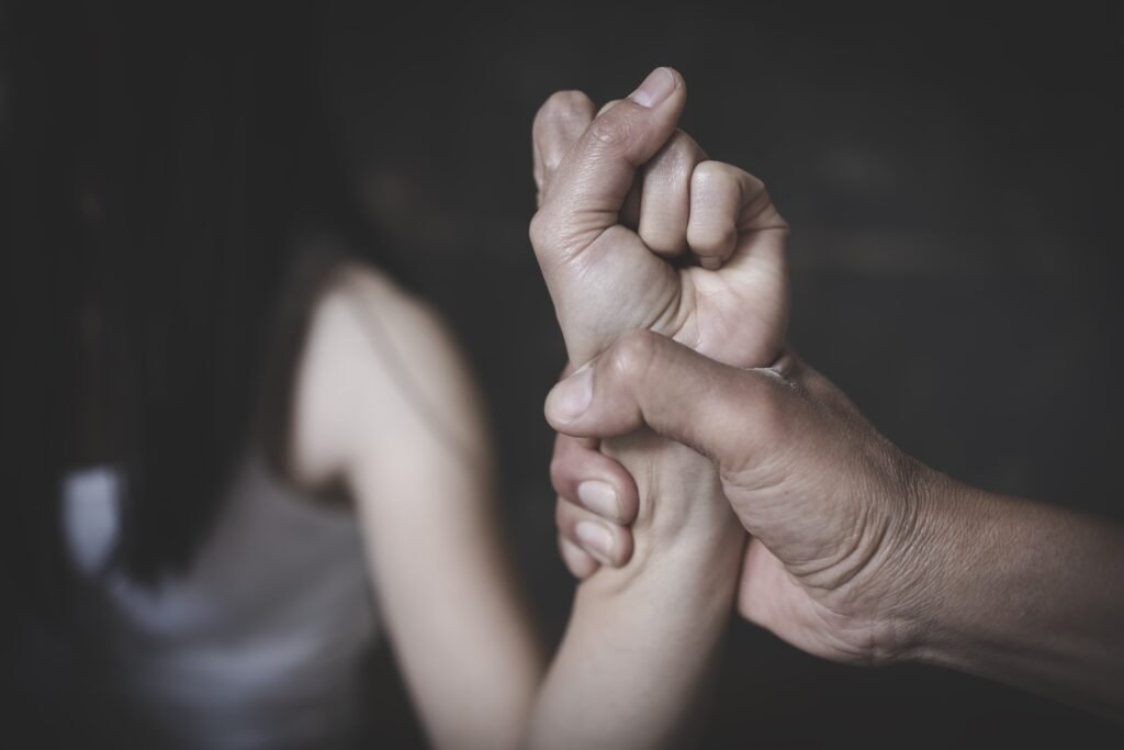 Przemoc w bliskich relacjach: Czy prawo chroni? Przemoc. Mężczyzna ściska za nadgarstek kobietę. Zdjęcie w szarościach