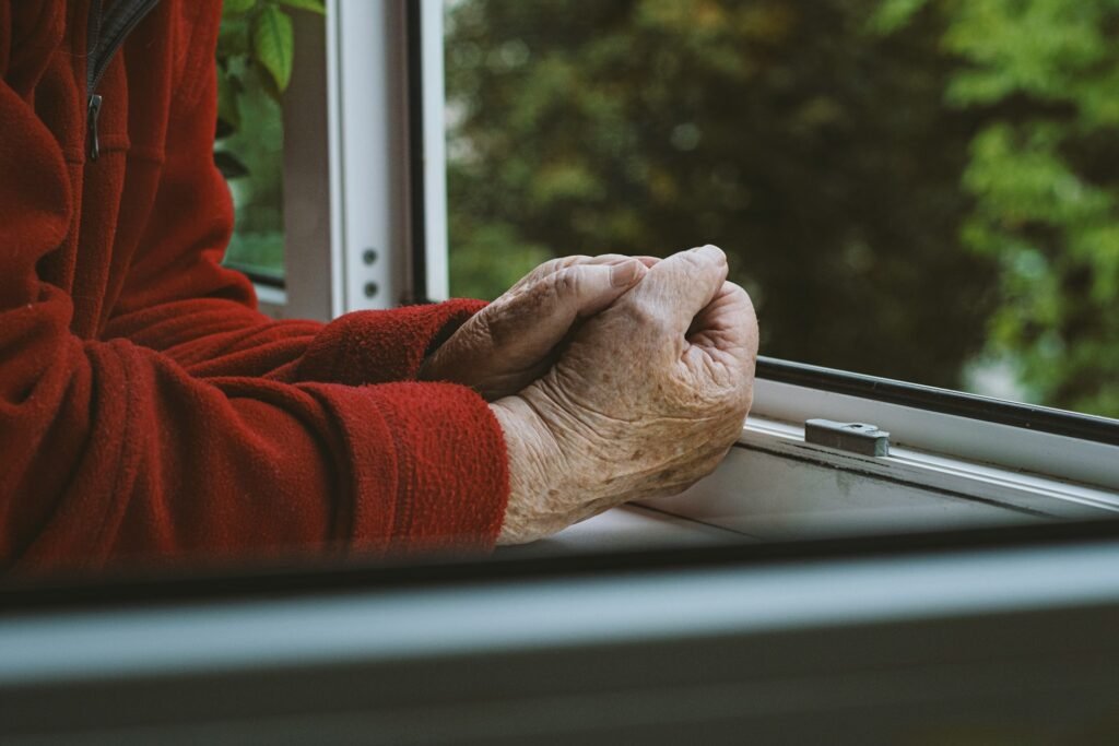 Uwaga, oszuści! Celują w seniorów Dłonie starszego mężczyzny, ubranego w czerwony sweter.