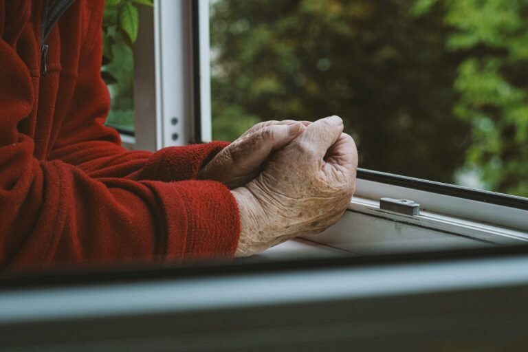 Dłonie starszego mężczyzny, ubranego w czerwony sweter.