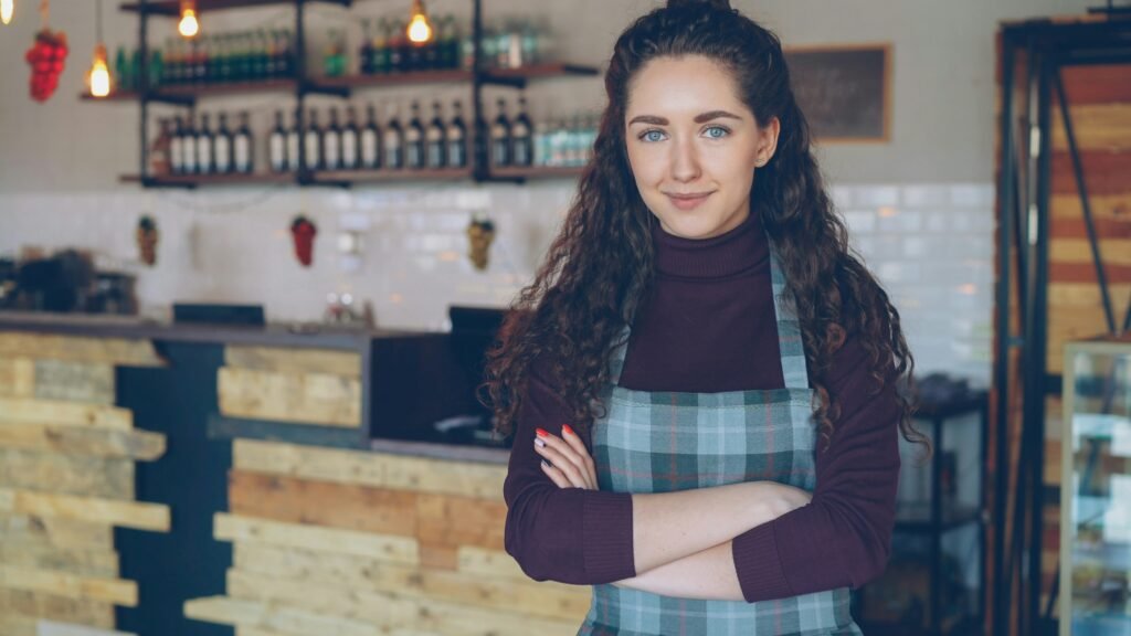 Praca sezonowa w Norwegii. Szansa na doświadczenie, zarobek i pierwsze zawodowe kontakty Młoda kobieta uśmiecha się na tle restauracji